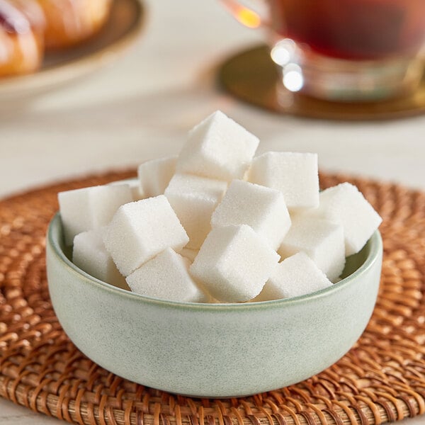 A bowl of Domino sugar cubes on a table.