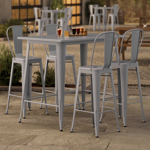 A Lancaster Table & Seating outdoor bar height table with four chairs on a patio.