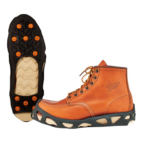 A close up of a brown boot with orange and black Ergodyne ice cleats on the bottom.