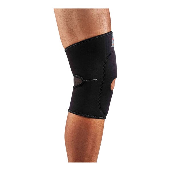 A person wearing a black Ergodyne ProFlex knee compression sleeve with open patella and anterior pad.