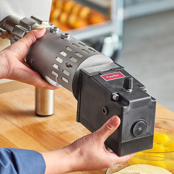 A person using an Estella pasta cutter attachment to cut pasta in a professional kitchen.