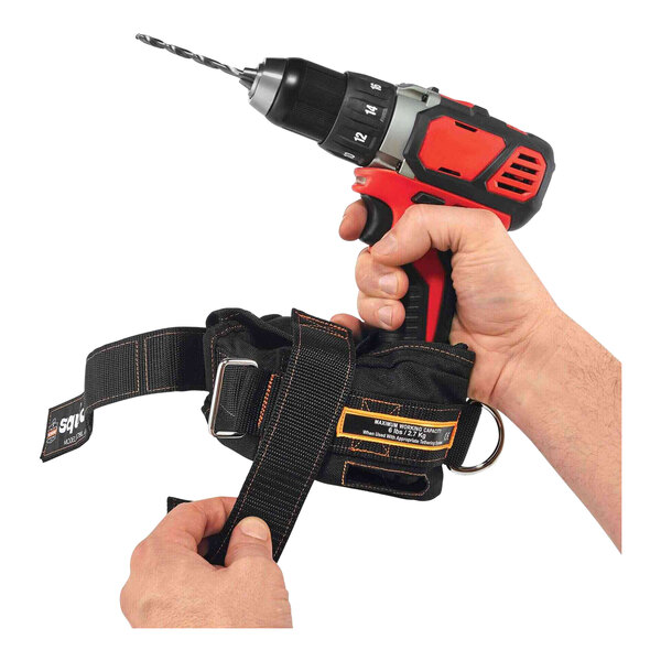 A hand holding a drill with a black tool strap attached to it.