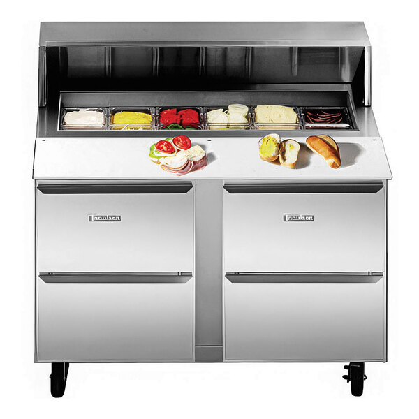 A Traulsen stainless steel sandwich prep table with two drawers on a counter with food.