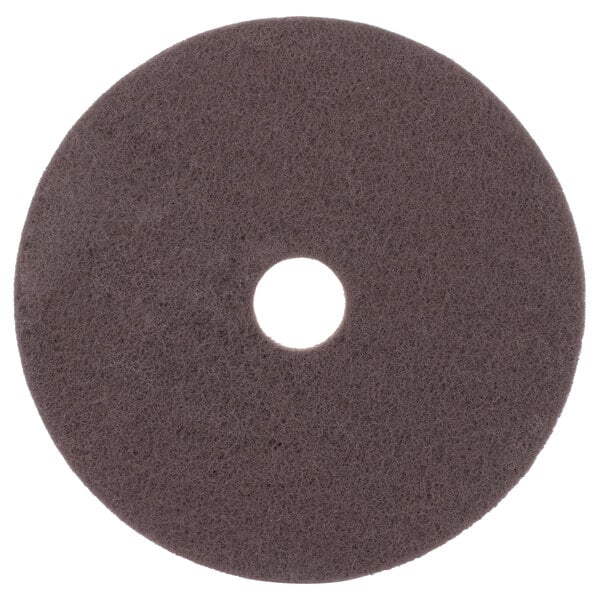 A brown circular Scrubble stripping floor pad with a hole in the middle.