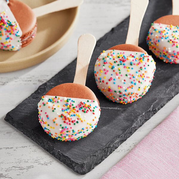 A group of Coco Bakery chocolate macarons with sprinkles.