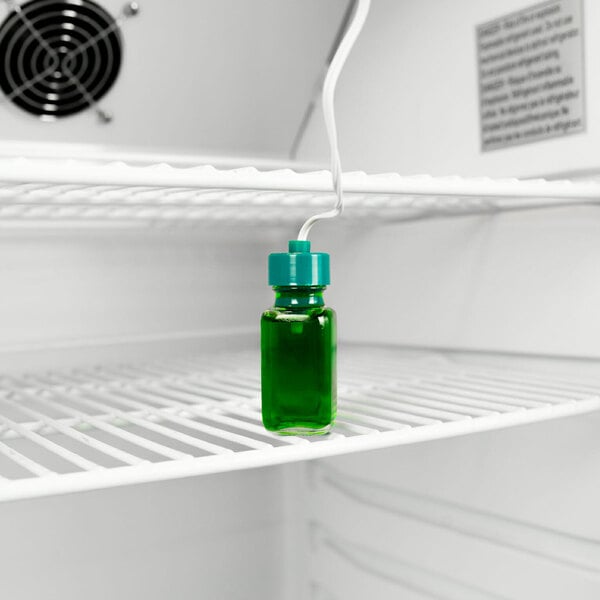 A green glass bottle with a white cap of green liquid in a Danby medical refrigerator.