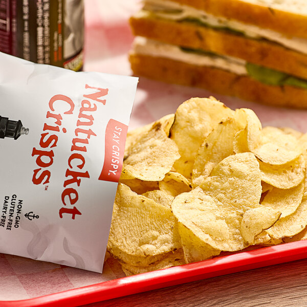 A red tray with a bag of Nantucket Crisps Sconset Sea Salt Potato Chips on it next to a sandwich.