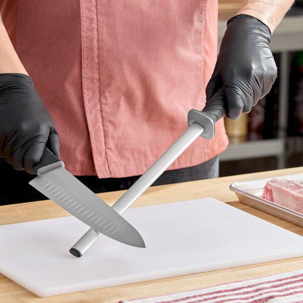 A 12-inch oval diamond sharpening rod with a TPR grip handle being used to hone a kitchen knife.