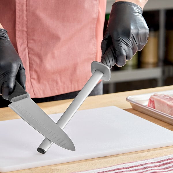 A 10-inch oval diamond sharpening rod with a TPRgrip handle being used to sharpen a kitchen knife.