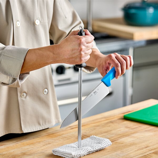 A person holding a knife on a cutting board using a Choice stainless steel sharpening rod.