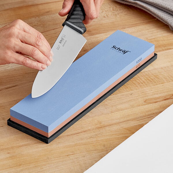 A person's hands sharpening a knife with a Schraf combination sharpening stone.