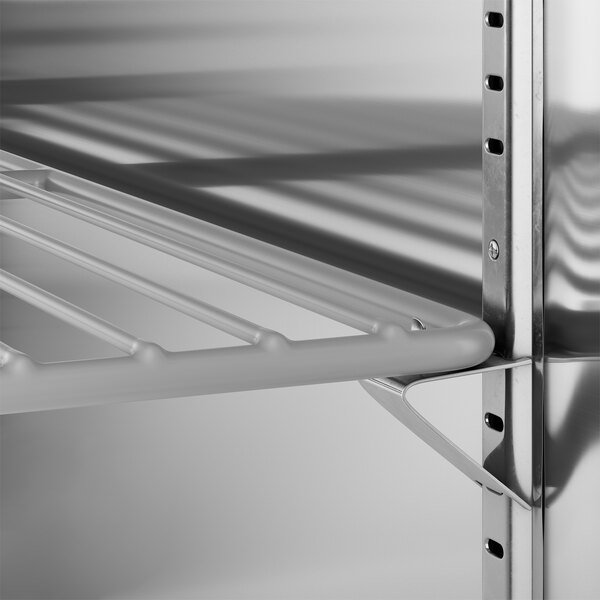 A metal shelf with holes inside a True back bar cooler.
