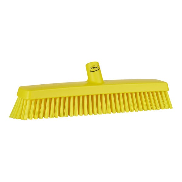 A yellow Vikan heavy-duty push broom head with soft and stiff bristles.