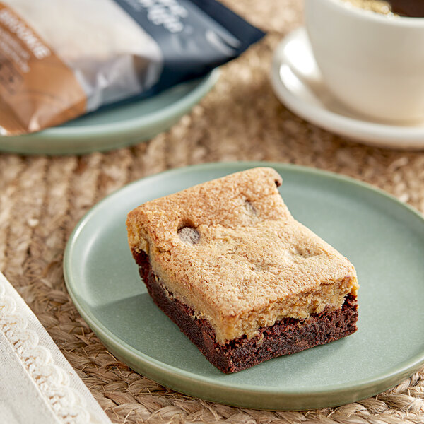 An individually wrapped Killer Brownie brookie on a plate with a cup of coffee.