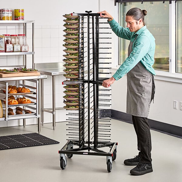 A man wearing an apron pushing a JackStack mobile plate rack full of plates.