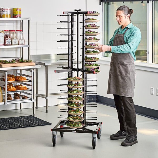 A man wearing a grey apron using a JackStack mobile plate rack in a kitchen.