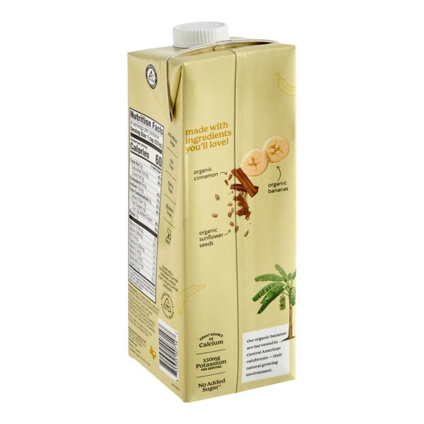 A beige carton with a white cap featuring images of banana slices, cinnamon sticks, sunflower seeds, and a banana tree, along with nutritional information and ingredient highlights on the side.