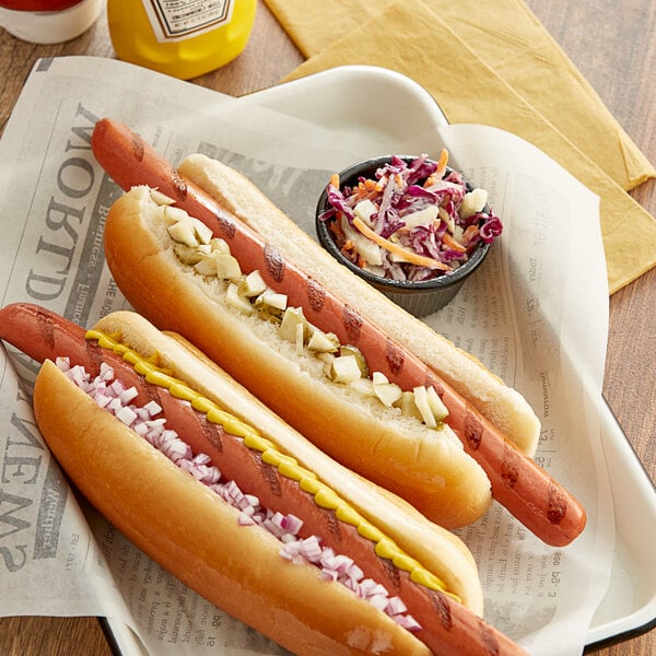 Two Sabrett beef hot dogs with mustard and pickles in a yellow container.