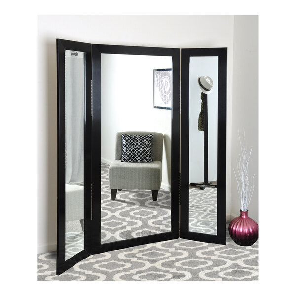 A BrandtWorks black stainless trifold dressing mirror in a room.