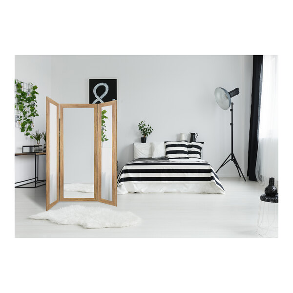 A BrandtWorks trifold dressing mirror in a room with a black and white striped rug and bedding.