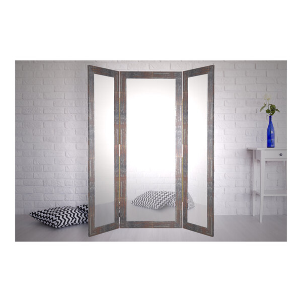 A BrandtWorks trifold dressing mirror with a faux metal frame.