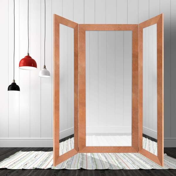 A BrandtWorks terracotta trifold dressing mirror in a room with two lamps.