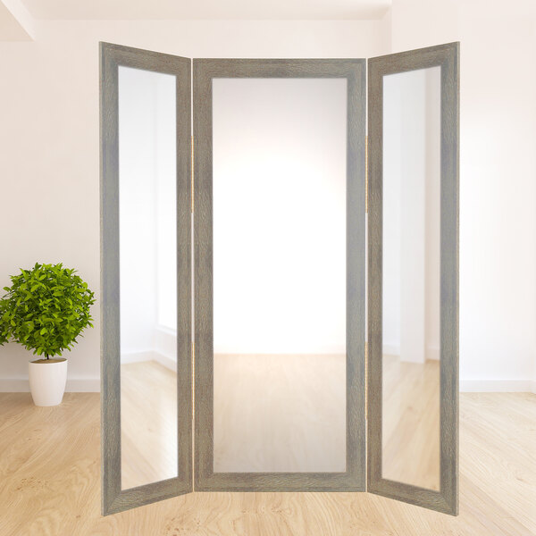 A BrandtWorks sage trifold dressing mirror in a room with a potted plant.