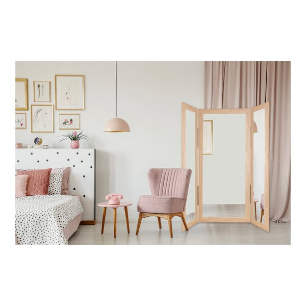 A BrandtWorks neutral tan trifold dressing mirror in a white room with a pink chair and table.