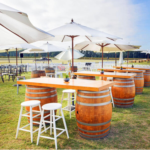 A white Mod-Picket umbrella on a wooden table with white chairs and a barrel with silver bands.