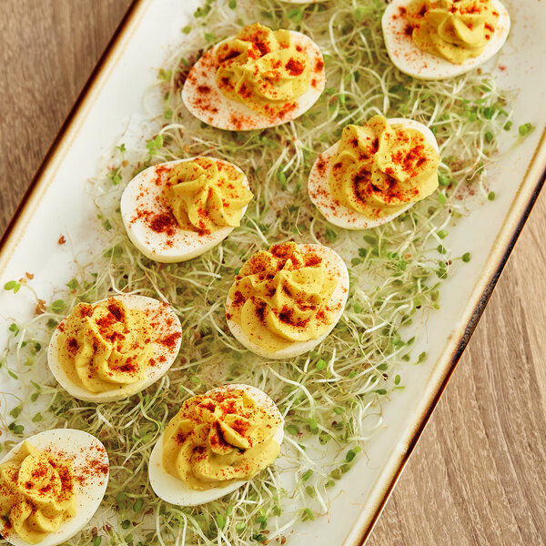 A plate of deviled eggs with red and yellow paprika toppings.