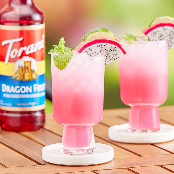 A pink drink made with Torani Dragon Fruit Flavoring Syrup in a glass garnished with fruit and mint.