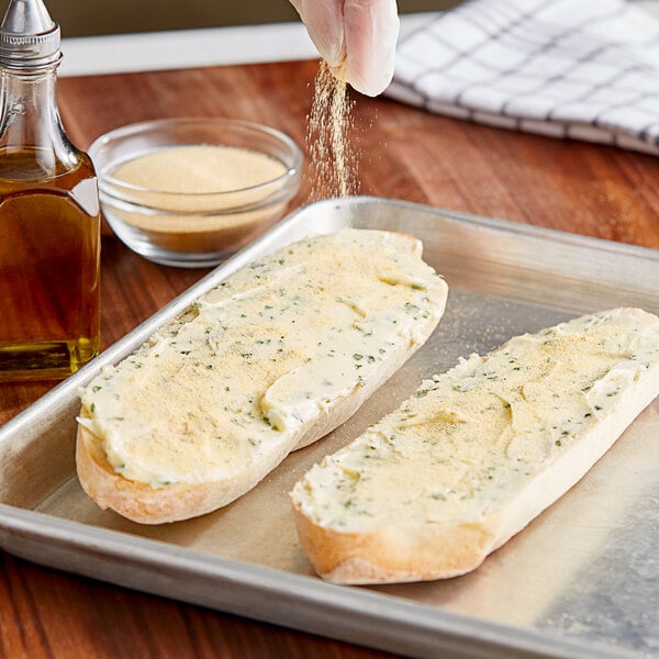 A person sprinkling McCormick Culinary Granulated Garlic on bread.