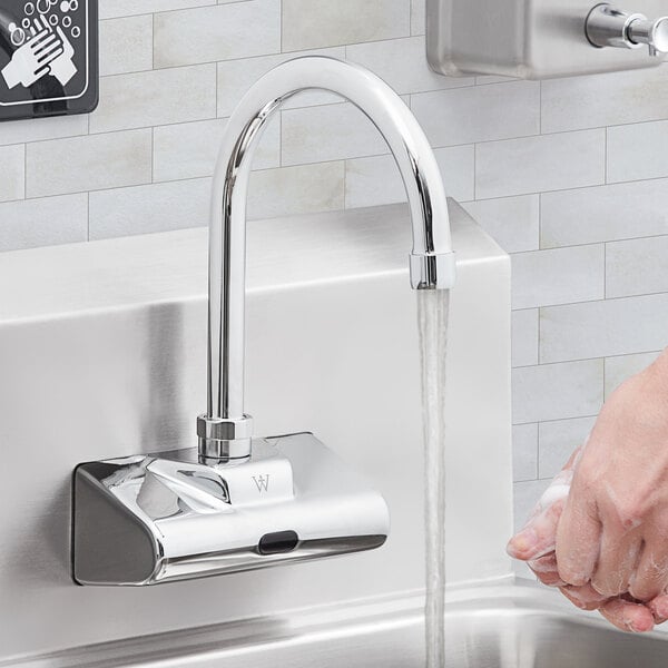 A person washing their hands with a Waterloo wall-mount hands-free sensor faucet.