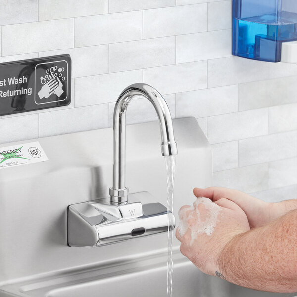 A person washing hands under a Waterloo wall-mount hands-free sensor faucet.