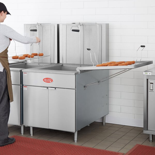 A man using an Avantco Liquid Propane Flat Bottom Funnel Cake Fryer in a commercial kitchen.