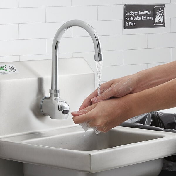 A person washing their hands under a Waterloo wall-mount hands-free sensor faucet.