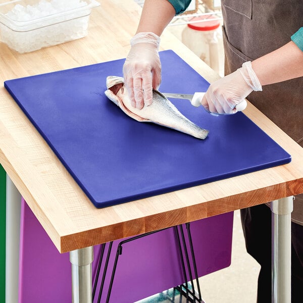 A person cutting fish on a blue Thunder Group cutting board.