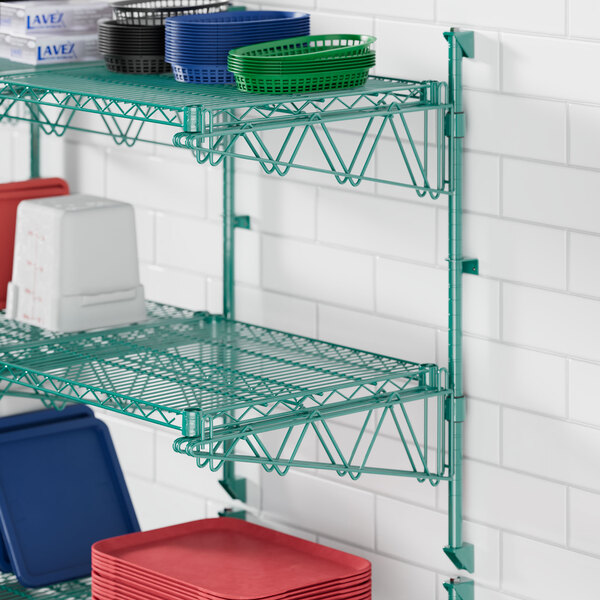 A Regency green metal wall shelf with red plates on it and a stack of red plates.