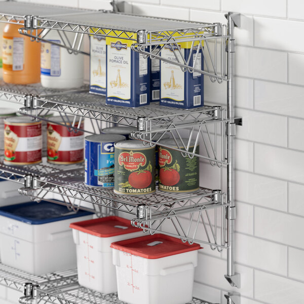 A Regency stainless steel wall-mounted wire shelf with cans and food containers on it.