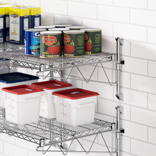 A Regency stainless steel wire shelf with food containers and cans on it, including white containers with red lids.