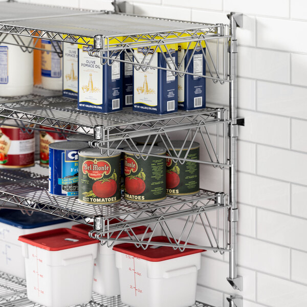 A Regency chrome wire wall shelf with food containers on it, including white and red plastic containers and cans of food.
