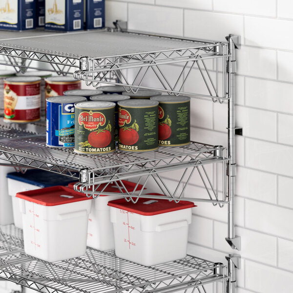 A Regency stainless steel wall-mount shelf with food cans and containers on it.