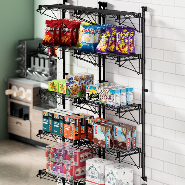 A black Regency wire wall-mount shelf with snacks on it.