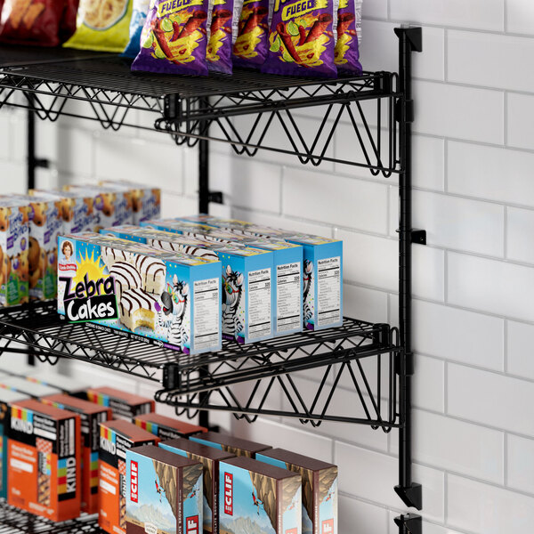 A Regency black wire wall shelf with food and snacks on it.