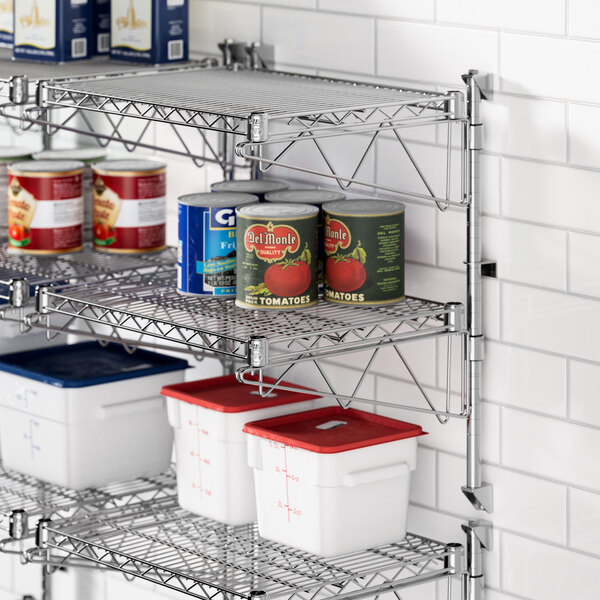 A kitchen with metal Regency wall-mounted shelves holding food cans and containers.