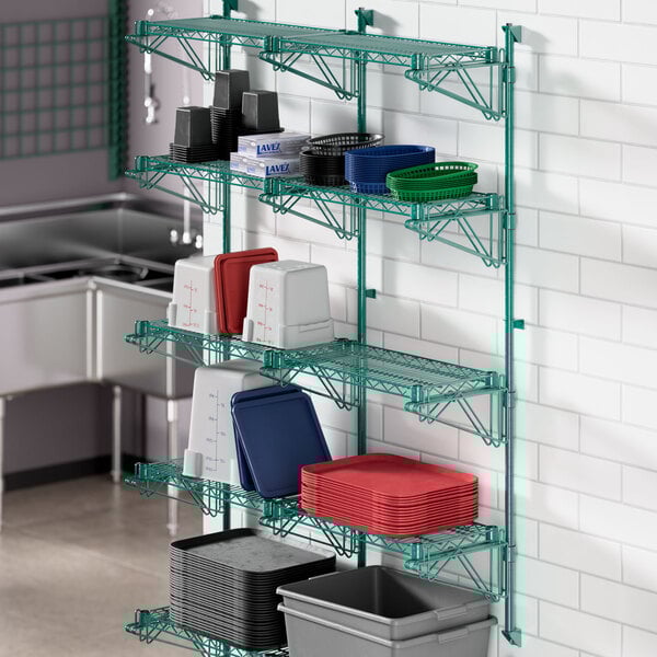 A green Regency wire shelving unit with dishes and containers on a shelf.