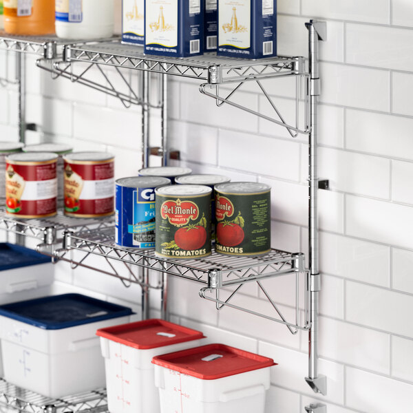 A metal Regency wall-mount shelf with cans of food on it.