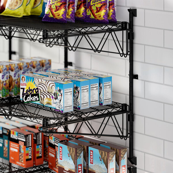A Regency wire shelving unit with a shelf holding boxes of snacks and zebra cakes.