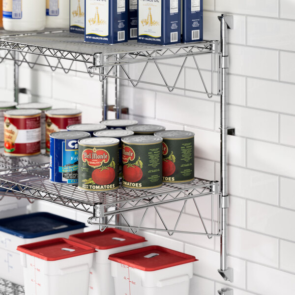 A Regency stainless steel wall-mount shelf with cans of food on it.
