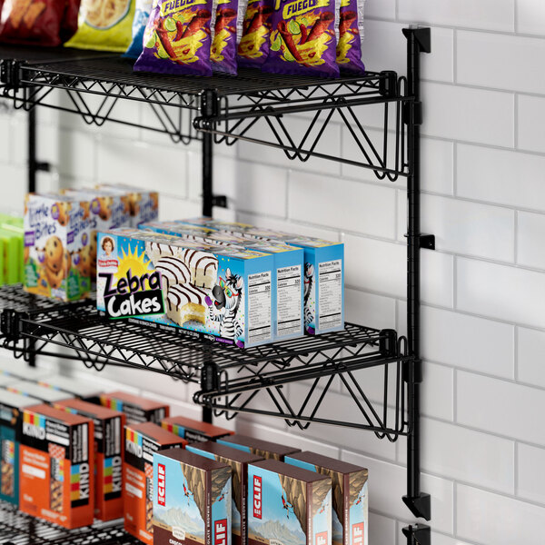 A Regency black wire wall shelf with food and snacks on it.